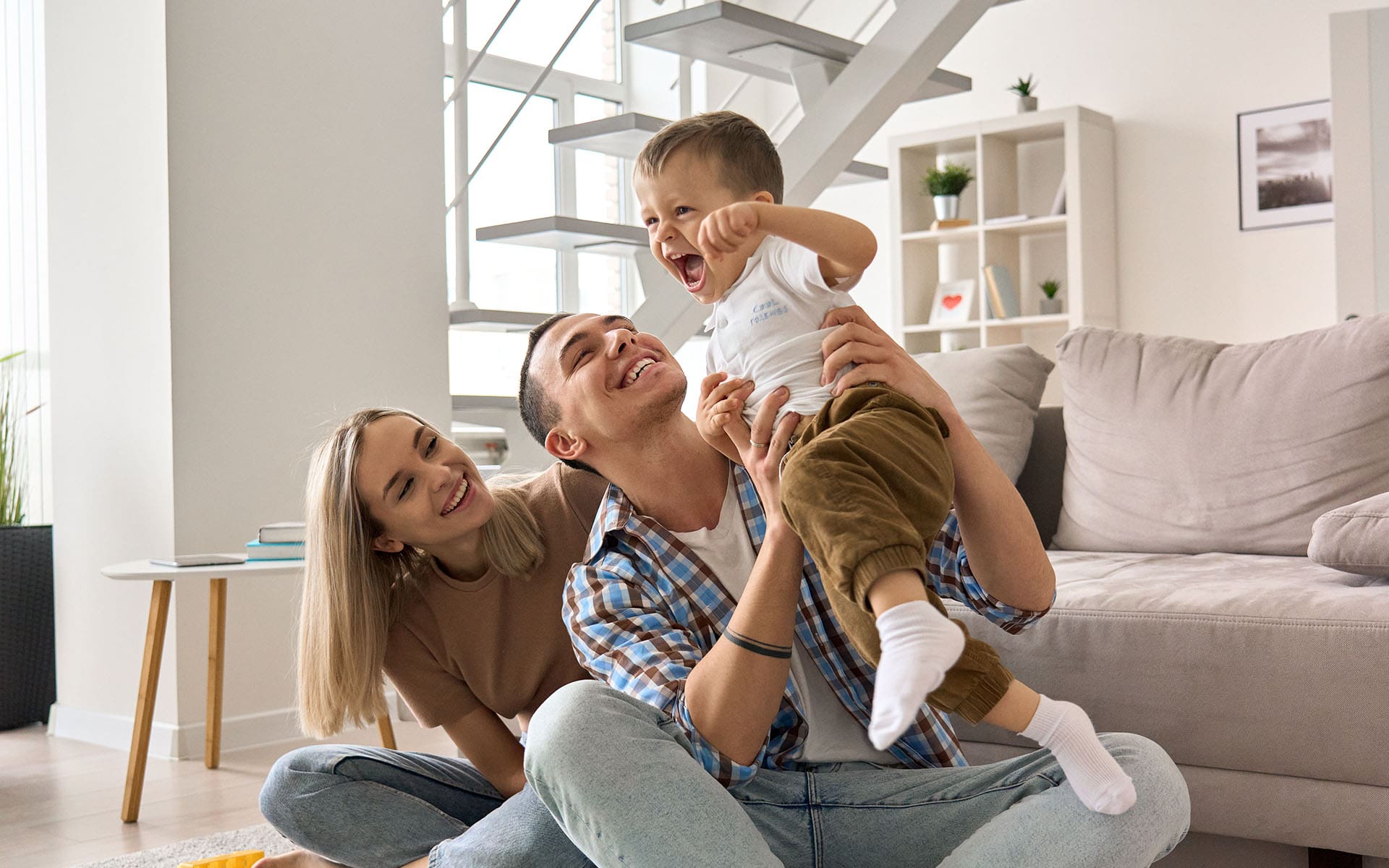 Oliver Insurance Agency - Happy young family couple Having Fun Playing With Cute Small Toddler Kid Son in Modern Living Room Together